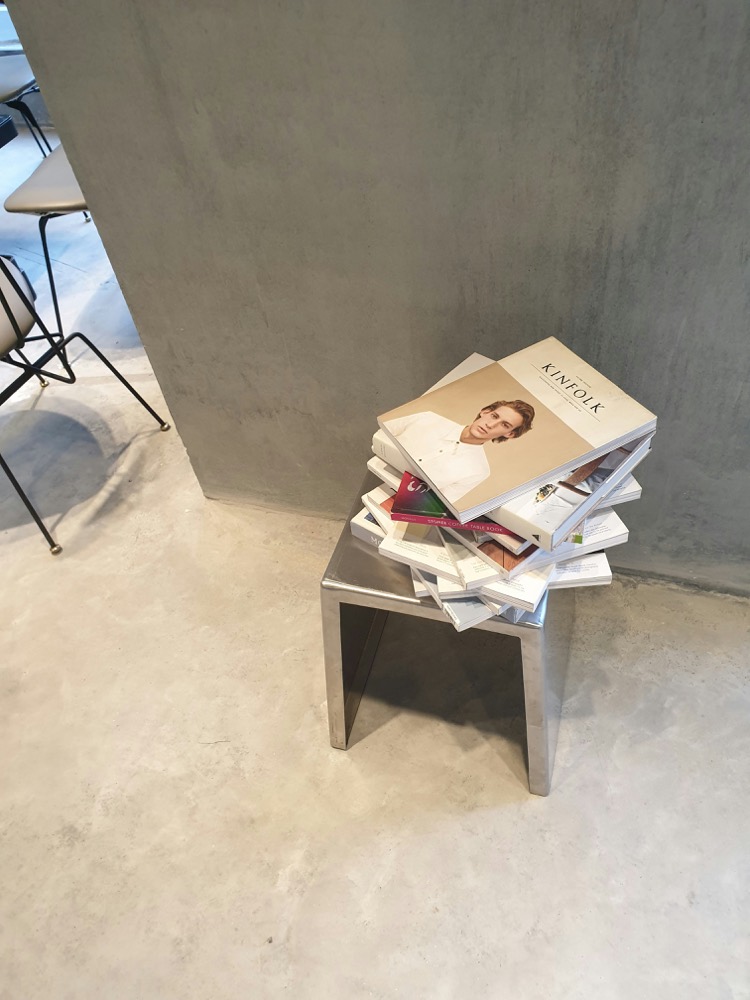 Stapel Magazine auf einem Edelstahl-Hocker vor Sichtbeton